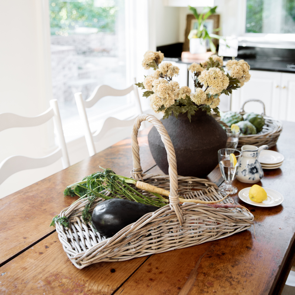 Wicker basket with vegetables on a wooden table in a kitchen setting
